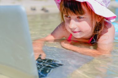 Uzaktan çalışma konsepti. Genç güzel kız deniz suyunda dizüstü bilgisayarla çalışıyor.. 