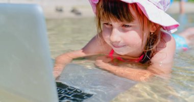 Uzaktan çalışma konsepti. Deniz suyunda dizüstü bilgisayarla çalışan genç ve güzel bir kız. Yatay resim.