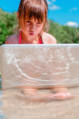 Deniz suyunda netbook ile uzaktan çalışan genç ve güzel bir iş kadınının portresi. Dikey resim.