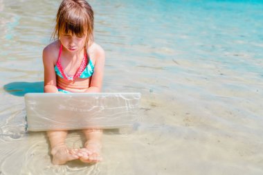 Deniz suyunda netbook ile uzaktan çalışan genç ve güzel bir iş kadınının portresi. Metin veya tasarım için boşluk kopyala.