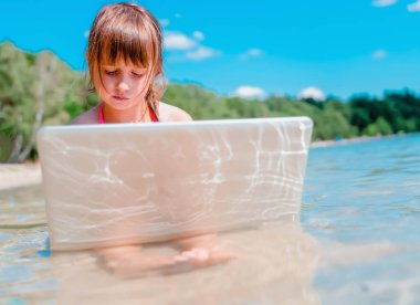 Aynı anda hem çalış hem dinlen. Genç kız tropikal denizin güzel sahillerinde uzaktan öğreniyor. Yatay görüntü. Boşluğu kopyala