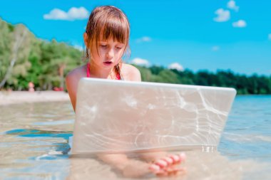 Kavramsal görüntü: Aynı anda çalış ve dinlen. Genç kız tropikal denizin güzel sahillerinde uzaktan öğreniyor. Yatay resim