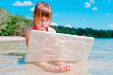 Her zaman ve her yerde öğrenmek. Güzel bir genç kızın portresi tropikal denizde dizüstü bilgisayarla uzaktan öğreniyor.. 