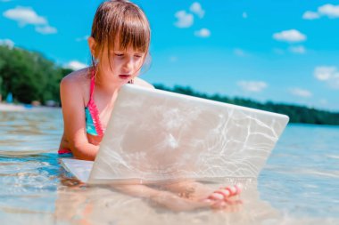 Her zaman ve her yerde öğrenmek. Güzel kız tropikal denizde dizüstü bilgisayarla uzaktan öğreniyor. Komik bir görüntü..