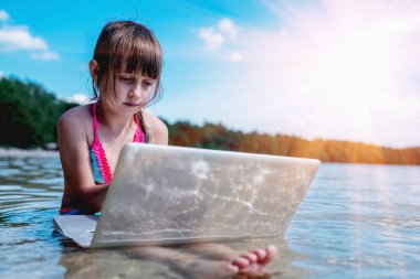 Bu yaz çalışanları ofisten nasıl çıkaracağız? Güzel genç iş kızı güzel tropikal plajda netbook ile uzaktan çalışıyor..