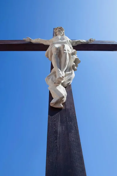 耶稣基督被钉在蓝天的十字架上的古老雕像的底部视图 垂直图像 — 图库照片