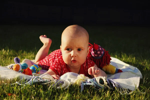 Rozkošná holčička leží na zelené letní trávníku — Stock fotografie