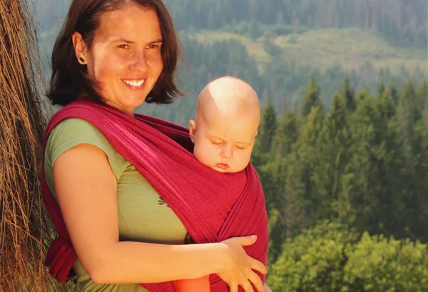 Mother carrying her baby in a sling — Stock Photo, Image