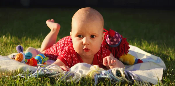 Adorable baby girl lying on green summer lawn — Stock Photo, Image