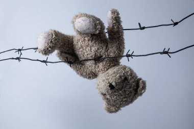 Çocukların hayatlarını ve hayallerini, çocukluklarını ve geleceğini kaybetti. Dikenli tellerde asılı kırık oyuncaklar. Yatay resim.