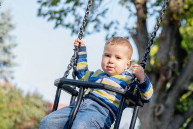 Kavramsal görüntü: Mutlu çocukluk. Yüksekten sallanırken bir çocuğun kahkahası havayı doldurur.