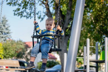 Kavramsal görüntü: Mutlu çocukluk. Küçük bir çocuk parkta özgürce sallanmaktan hoşlanıyor..
