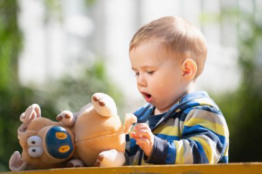 Kavramsal görüntü: Mutlu çocukluk. Gülümseyen bir çocuk bahçede yumuşak bir oyuncakla oynar..