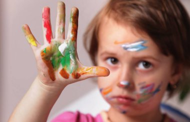 Çocuk resim dolu bir eli gösteriyor, sanatsal oyun özgürlüğünün tadını çıkarıyor.