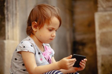 Kız sessizce oturuyor, hareketli bir oyuna dalmış..