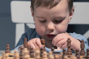 Ufaklık bir sonraki satranç hamlesini düşünüyor. Muhtemelen şekerleme molalarını, abur cubur stratejilerini ve uzun vadeli şampiyonluk hırslarını hesaplıyor..
