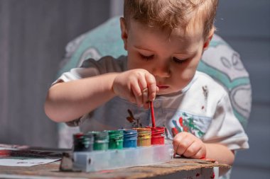 Yürüyen çocuk boya ve fırça kullanarak motor becerilerini geliştiriyor..