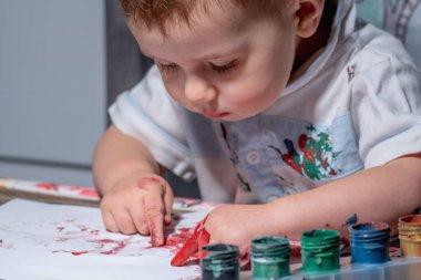 Yeni yürümeye başlayan çocuk parmak boyama yoluyla motor becerilerini geliştiriyor..