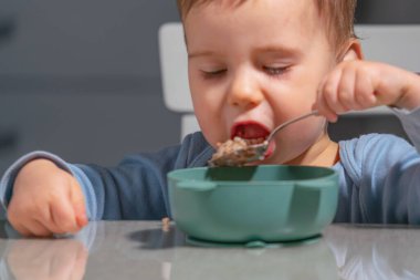 Çocuk dengeli çocuk diyetinin bir parçası olarak besleyici yulaf lapasının tadını çıkarıyor..