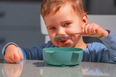 Bebek evde sağlıklı kahvaltı yaparken kaşıkla besleyici bebek lapası yiyor..