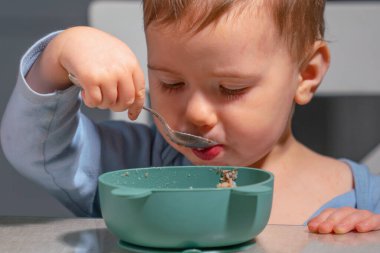 Bağımsız çocuk sağlıklı sabah alışkanlıklarının bir parçası olarak yulaf ezmesi yiyor..