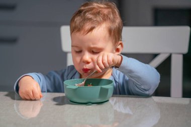 Çocuk besleyici kahvaltıdan zevk alırken kendini besleme becerilerini geliştiriyor.