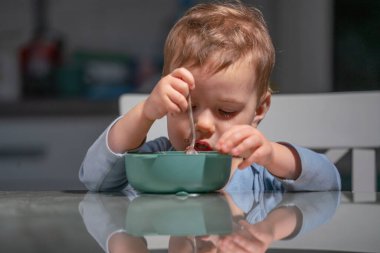 Yeni yürümeye başlayan çocuk, bağımsızlık öğrenirken besleyici bir kahvaltı yapıyor..