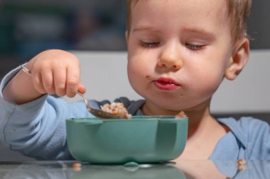 Kendi kendini besleyen çocuk evde besleyici mısır gevreğinin tadını çıkarıyor..