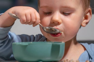 Bebek elleriyle yulaf ezmesi yerken motor becerilerini geliştiriyor..