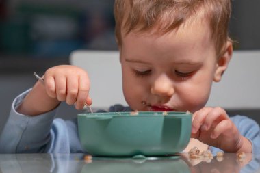 Yeni yürümeye başlayan çocuk, ebeveynlerinin yardımı olmadan mısır gevreği yiyerek bağımsızlığını kazanıyor..