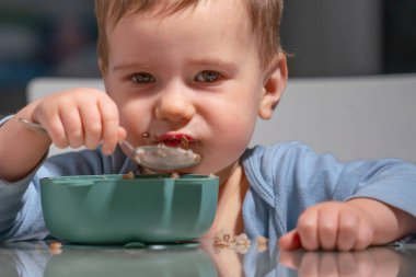 Çocuk sakin aile kahvaltısı sırasında besleyici yulaf ezmesinin tadını çıkarıyor..