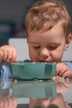 Bebek kendi başına yulaf ezmesi yerken sağlıklı kahvaltı kavramı..