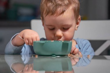 Çocuk masada yulaf ezmesi yerken kendini beslemeyi öğreniyor..