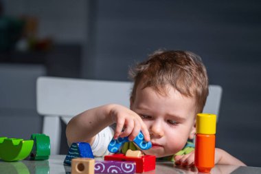 Çocuk oyun oynayarak öğrenirken sakin bir ev ortamında tahta bloklar yığıyor..