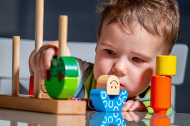 Çocuk dokunarak öğreniyor, ahşap blokları evin içine yığıyor..