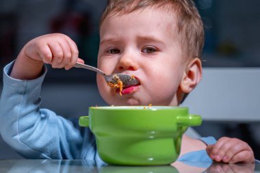 Bebek yeşil kaseden renkli meyve salatası yerken sağlıklı yiyecekler keşfediyor..