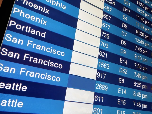 Arrivals display board at airport terminal — Stock Photo, Image