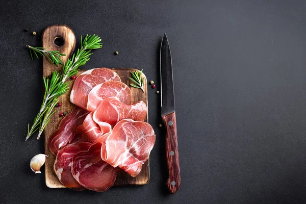 Prosciutto ham on dark background — Stock Photo, Image