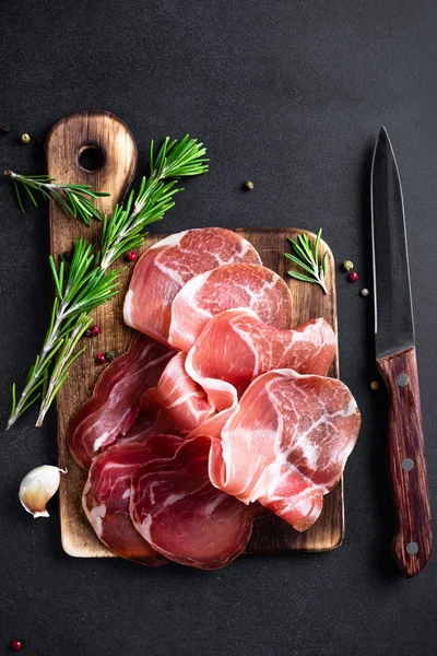 Prosciutto ham on dark background — Stock Photo, Image