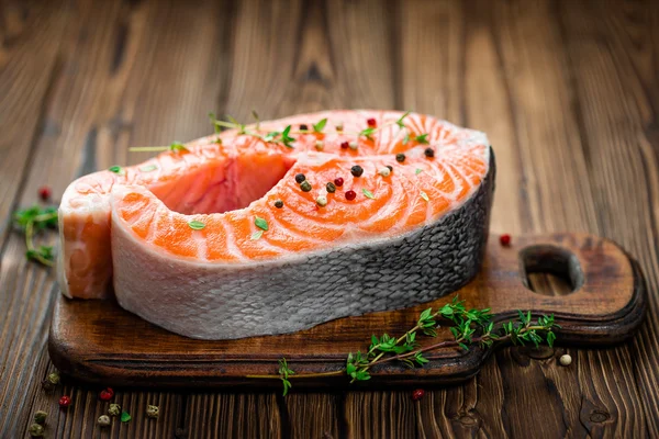 Bistecca di pesce crudo di salmone su sfondo rustico in legno — Foto Stock