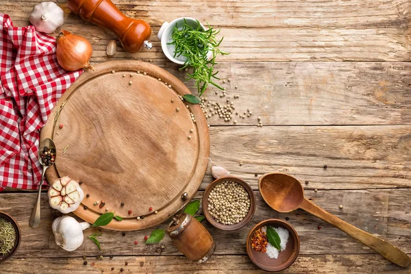 Culinaire achtergrond met lege snijplank en specerijen op de houten tafel — Stockfoto