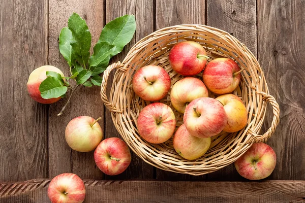Manzanas rojas frescas en canasta de mimbre sobre mesa de madera . — Foto de Stock