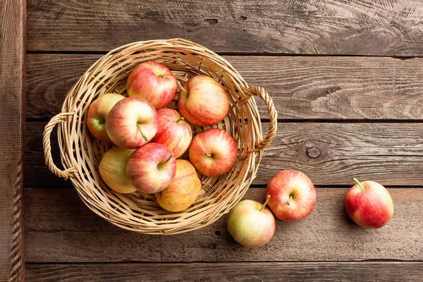 Verse rode appels in rieten mand op houten tafel. — Stockfoto