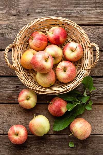 Manzanas rojas frescas en canasta de mimbre sobre mesa de madera . — Foto de Stock