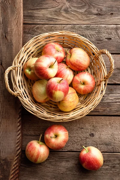 Verse rode appels in rieten mand op houten tafel. — Stockfoto