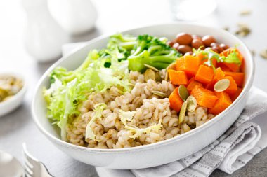 İnci arpalı, kırmızı fasulyeli, brokolili ve tereyağlı vejetaryen yemek kasesi.