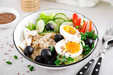 Sağlıklı kahvaltı için taze salatalık, dolma biber, zeytin, marul, feta peyniri, turp filizi ve rafadan yumurta ile Yunan esinlenmiş lezzetli yulaf ezmesi.