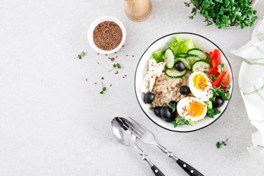 Sağlıklı kahvaltı için taze salatalık, dolma biber, zeytin, marul, feta peyniri, turp filizi ve kaynamış yumurta ile Yunan baharatlı yulaf ezmesi.