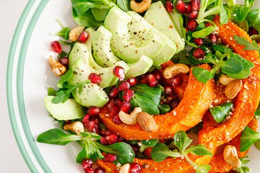 Kuzu marullu taze sebze salatası, fırında tereyağlı kabak ya da balkabağı, avokado, nar, kaju ve badem fıstığı. Sağlıklı vejetaryen gıda konsepti. Üst görünüm