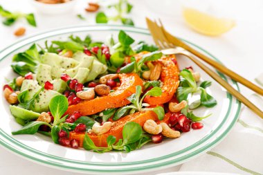 Kuzu marullu taze sebze salatası, fırında tereyağlı kabak ya da balkabağı, avokado, nar, kaju ve badem fıstığı. Sağlıklı vejetaryen gıda konsepti.